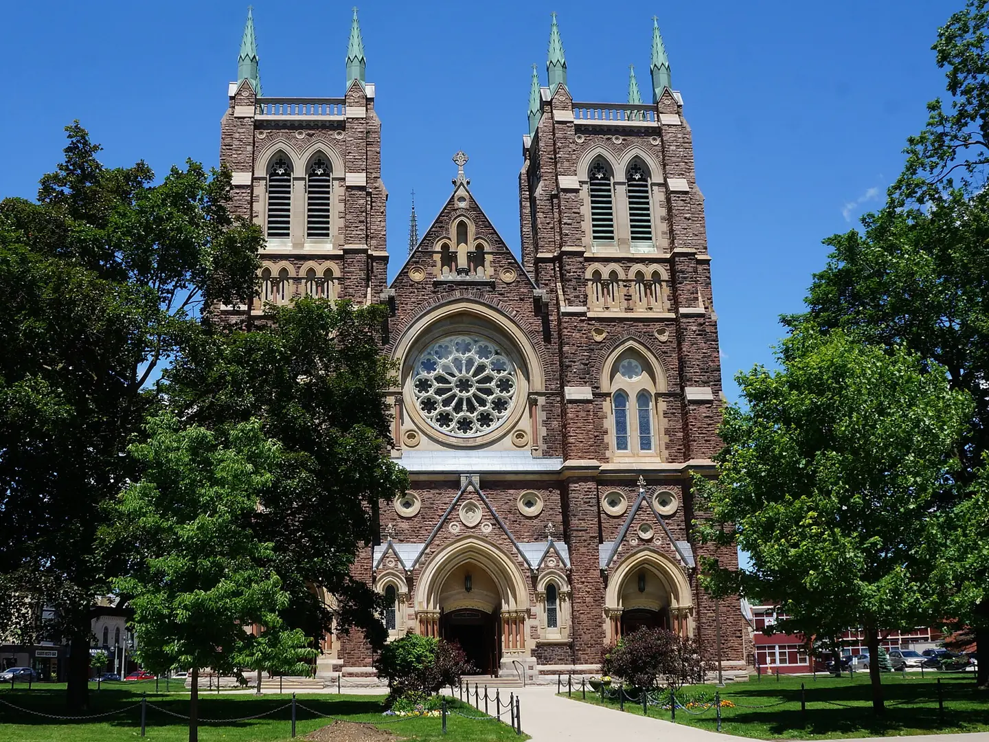 The front facade of St. Peter's Cathedral Basilica in London, Ontario, a stone Gothic church with twin towers and a rose window.