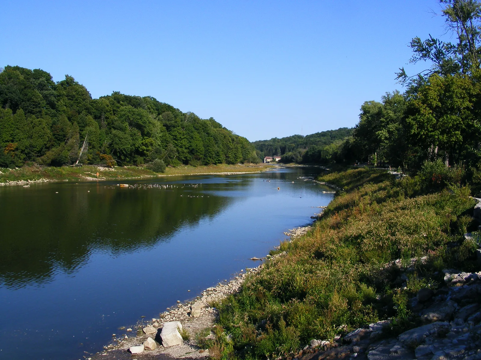 The Thames River in Springbank Park, London, Ontario, a wide daylight view with a forested far bank and a rocky near shore.